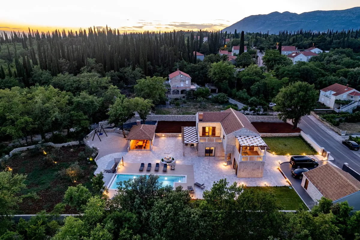 Aerial view of the villa and the Konavle countryside at dusk, mountains behind