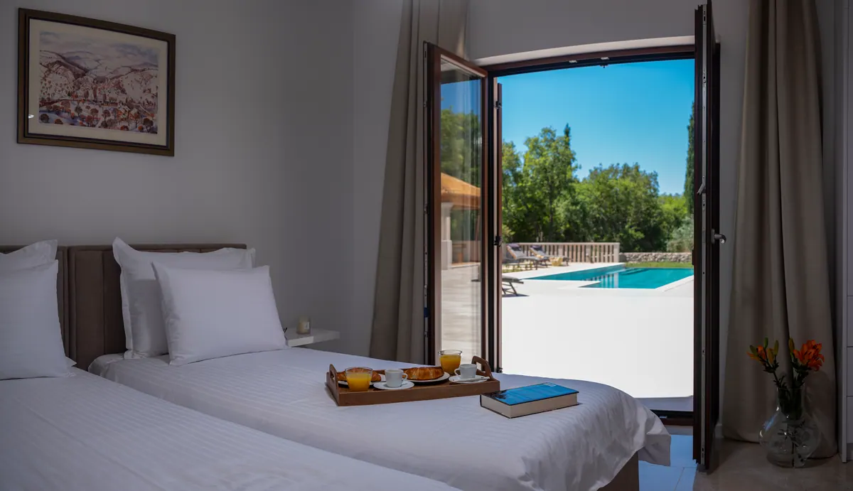 The twin bedroom with doors open to the pool terrace
