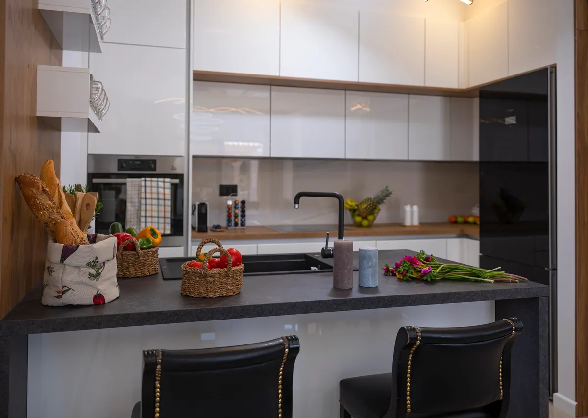 The kitchen with a dark stone breakfast bar and white cabinets