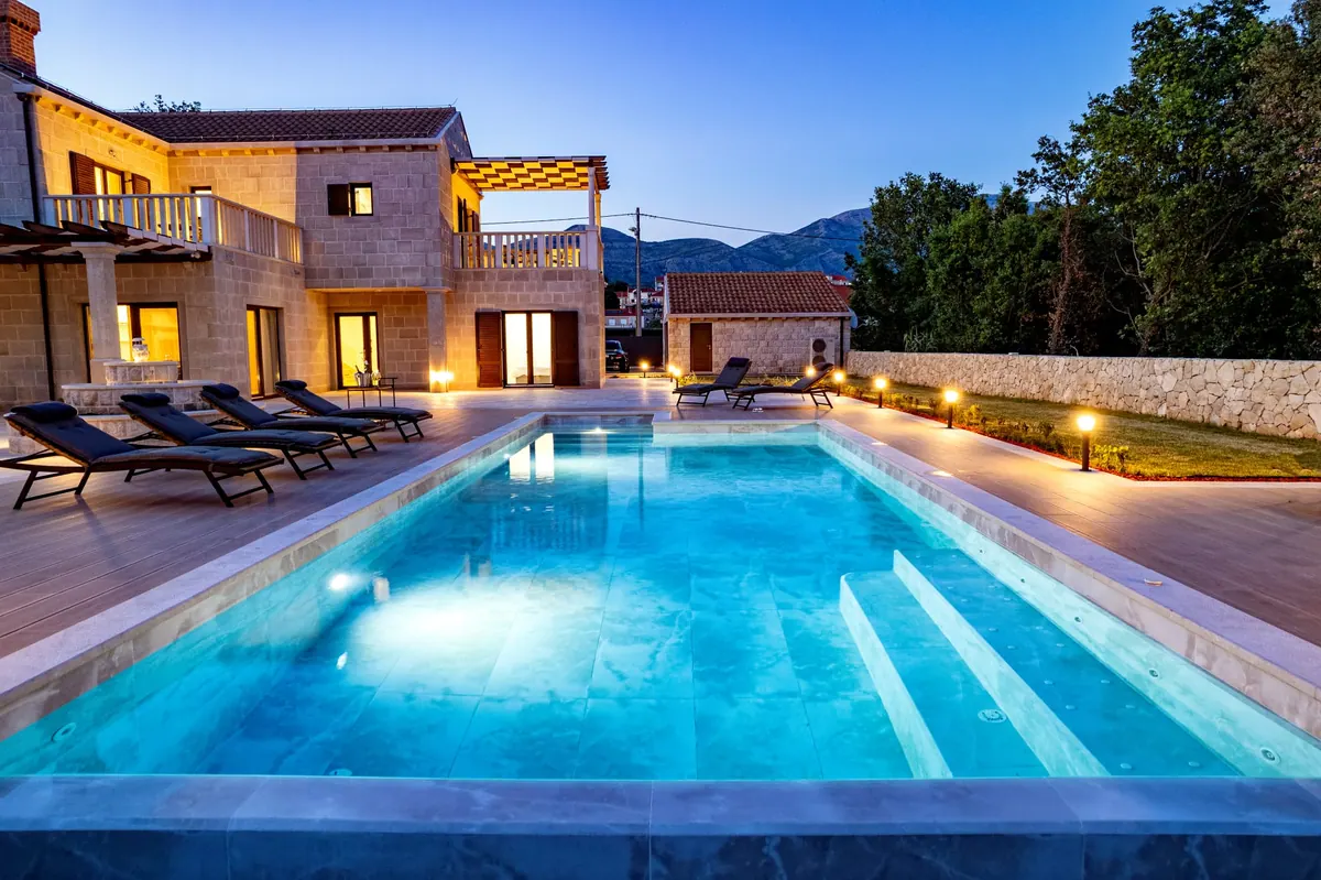 The pool lit at dusk with the villa behind