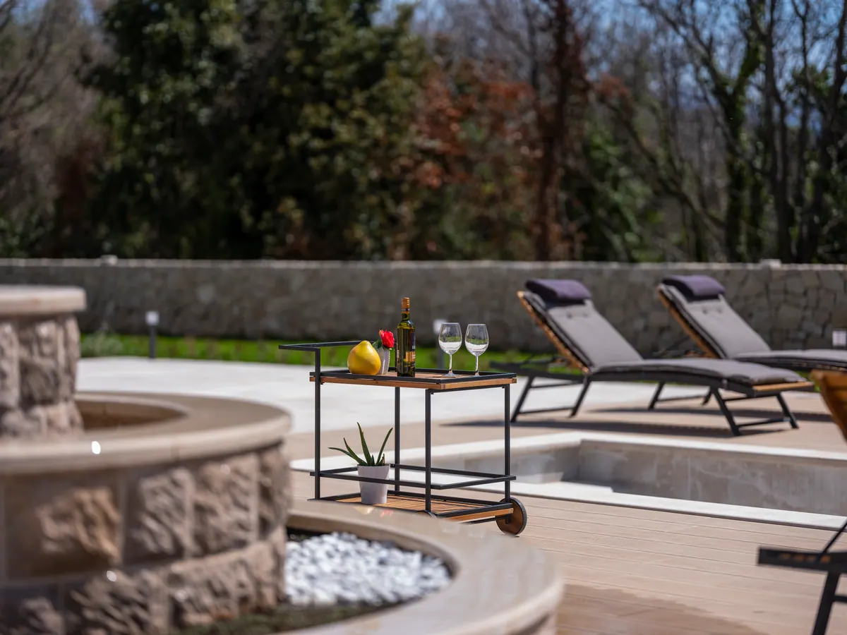 A drinks trolley by the stone fountain and the pool