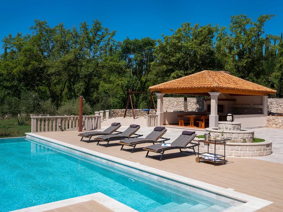 Loungers along the pool and the pavilion under the trees