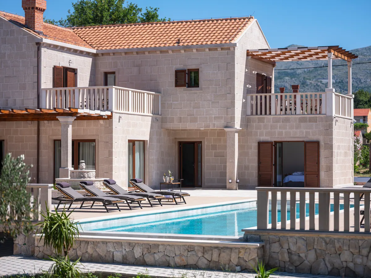 The stone façade with white balustrades above the pool