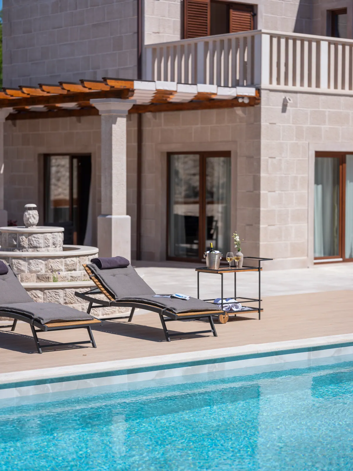 The stone villa and loungers seen from the pool